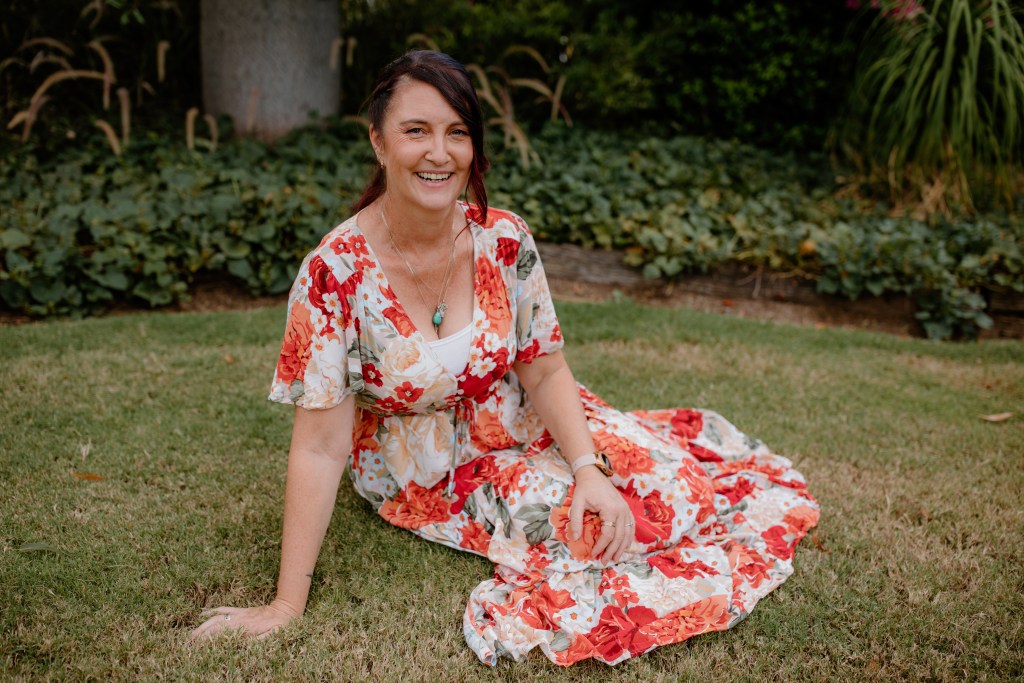 woman in floral dress sitting on grass in a garden